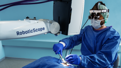 Mann am 3D-Operationsmikroskop RoboticScope