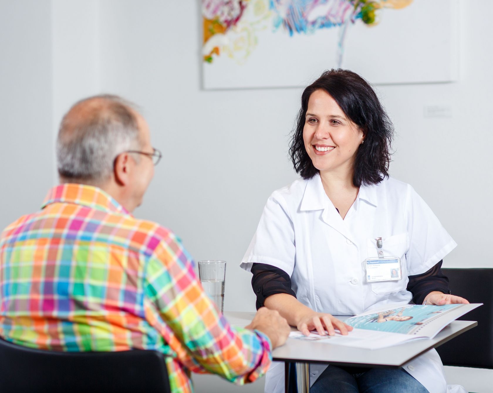 Eine Ärztin zeigt einem Patienten eine Broschüre