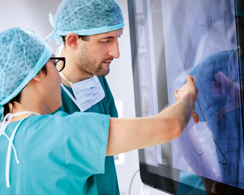Ein Chirurg und eine Chirurgin besprechen eine Röntgenaufnahme