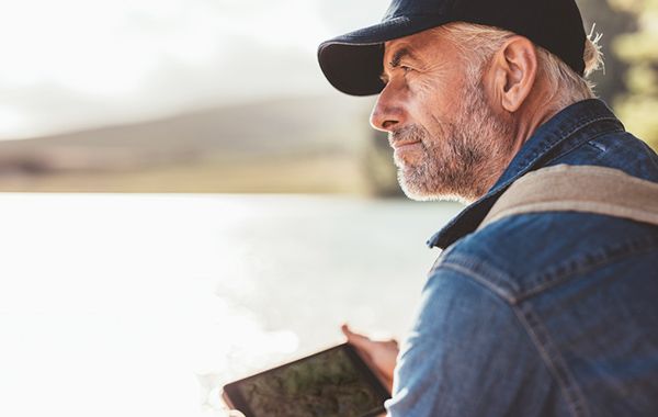 Mann sitzt an einem See und schaut in die Ferne