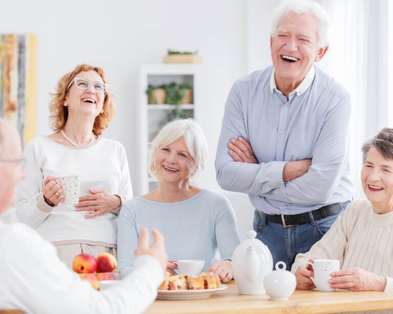 Ältere Menschen sitzen am Tisch und lachen zusammen
